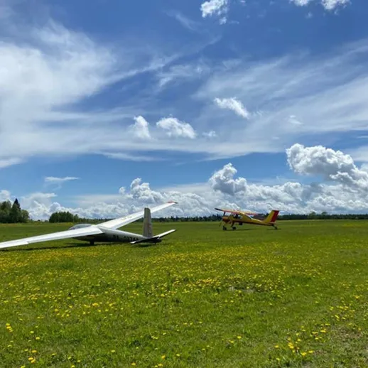 Летательный аппарат на травяном поле под голубым небом в солнечный день с облаками