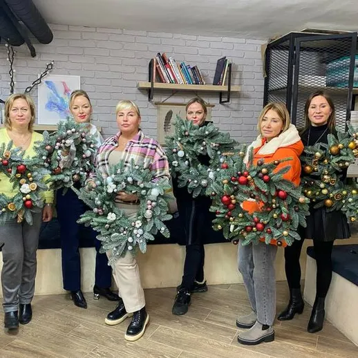 Женщины создают рождественские венки в уютной мастерской в зимний день