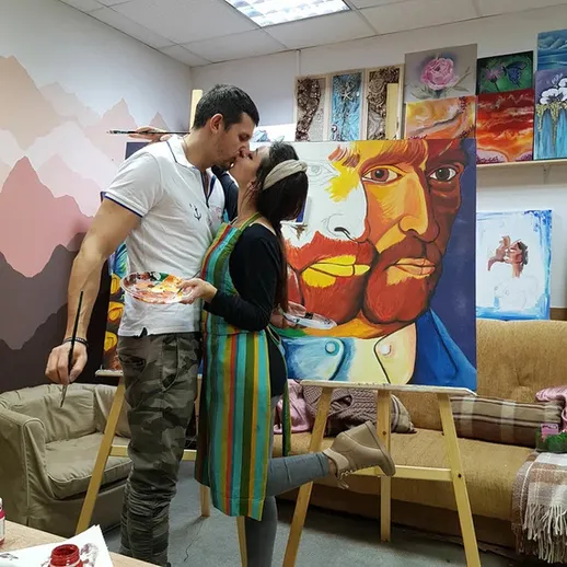 Молодая пара целуется во время рисования картины в художественной студии