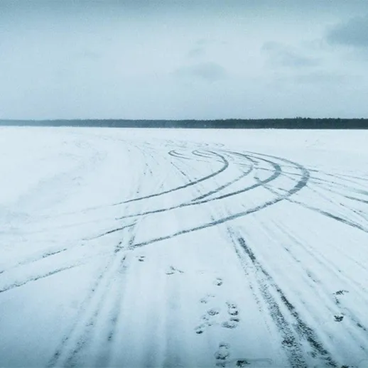 Автомобиль на зимнем озере с следами на снегу, прохладная погода, ясный день
