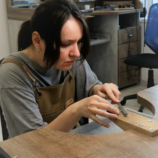 Молодая женщина работает над деревянным изделием в мастерской