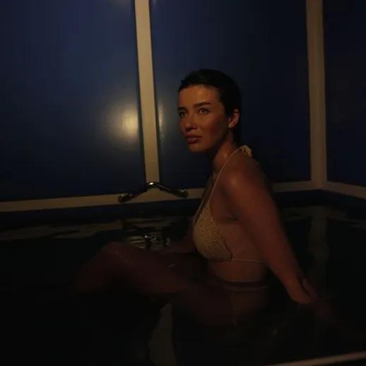 Женщина в воде с приглушенным светом, создающим атмосферу таинственности и спокойствия в уединенной обстановке