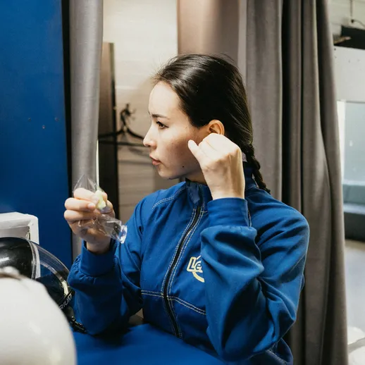 Молодая женщина в синем спортивном костюме готовится к тренировке в спортивном зале