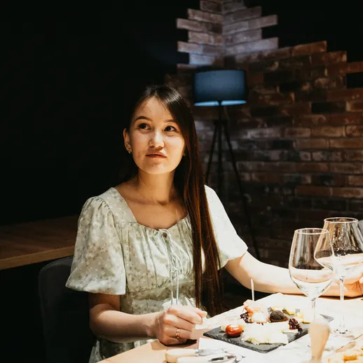 Женщина за столом в уютном ресторане, наслаждаясь ужином в вечернее время