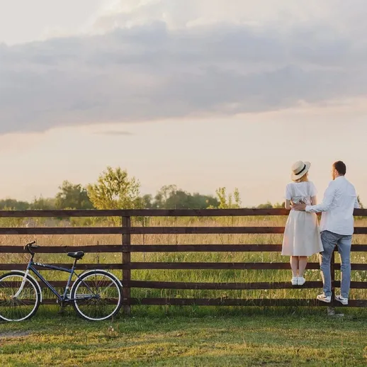 Романтическая прогулка пары на фоне заката у деревянного забора во время летнего вечера