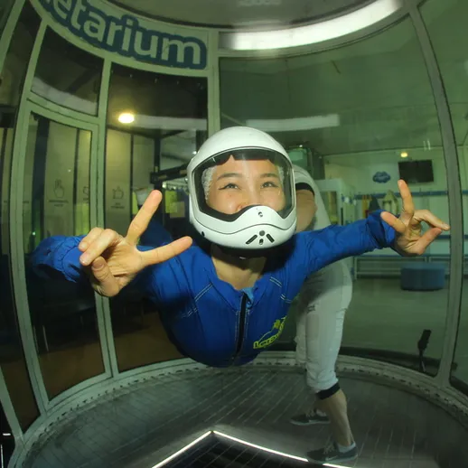 Человек в воздухе в куполе для свободного падения в помещении, спортивный опыт в центре аттракционов