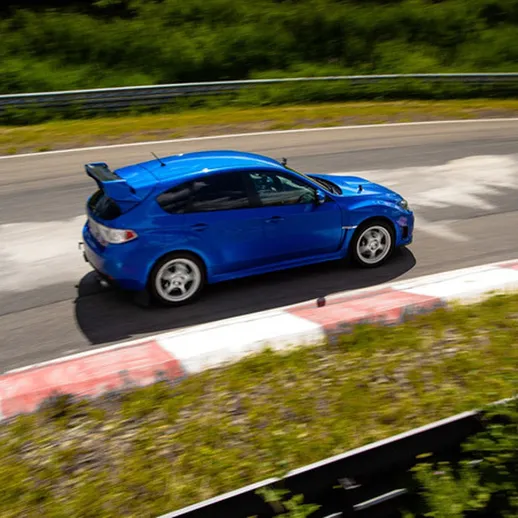 Спортивный автомобиль на гоночном треке, преодолевающий поворот в солнечный день