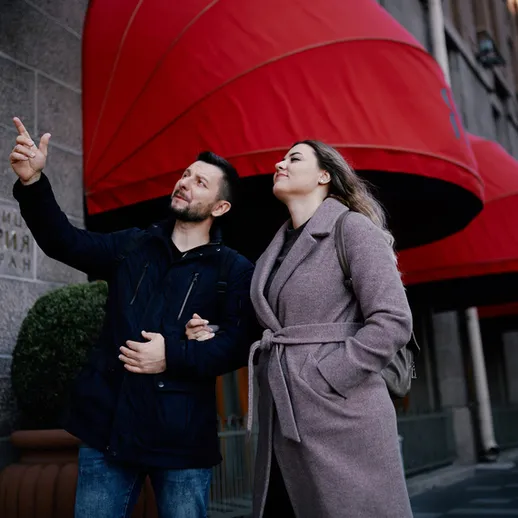 Романтическая прогулка пары возле ресторана с яркими навесами в центре города