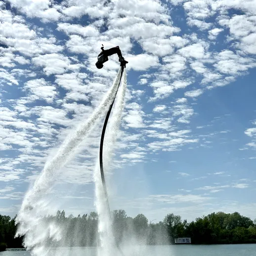 Водный спорт на реке: человек на водном дельфине выполняет акробатические трюки под ясным небом