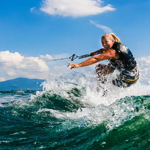 Прыжок на вейкборде на фоне гор и голубого неба в солнечный день у озера