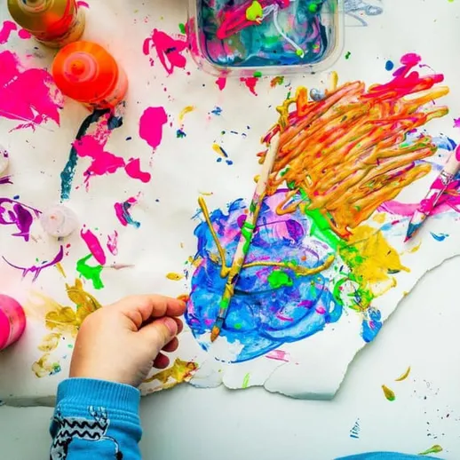 Яркое творчество ребенка с разноцветными красками на бумаге в домашней мастерской весной