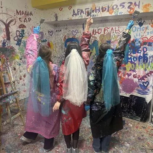 Четыре девушки с краской на одежде в творческой мастерской в центре города