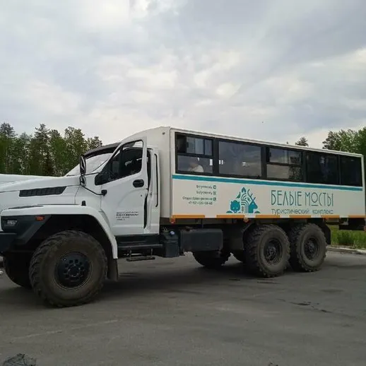 Грузовик с туристическими мостами на фоне облачного неба в российской природе