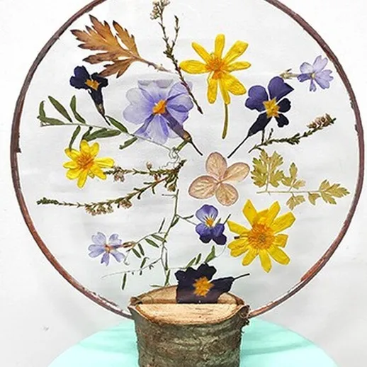 Красивый венок из сушеных цветов на круглом подвесе в интерьере на фоне светлой стены