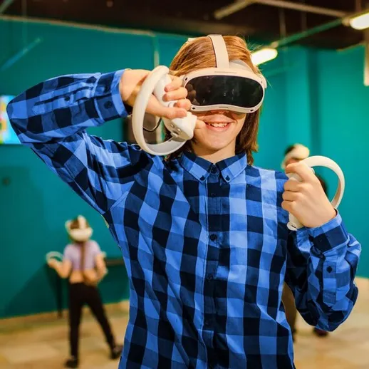 Мальчик в виртуальной реальности наслаждается игрой в игровом центре, демонстрируя радость и увлечение