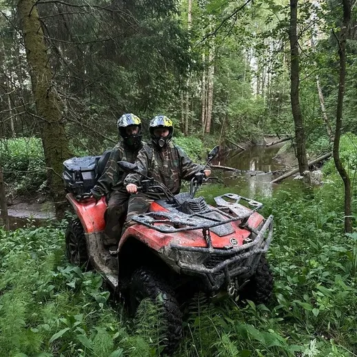 Два человека на квадроцикле в лесу во время дождя