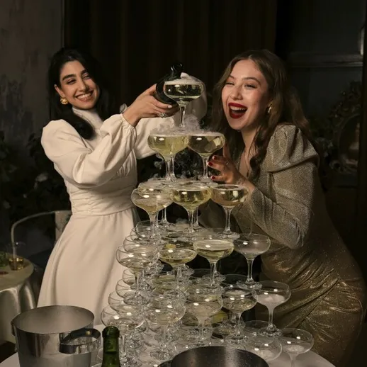 Женщины подают напитки в стеклянные бокалы на торжественном празднике в вечернее время