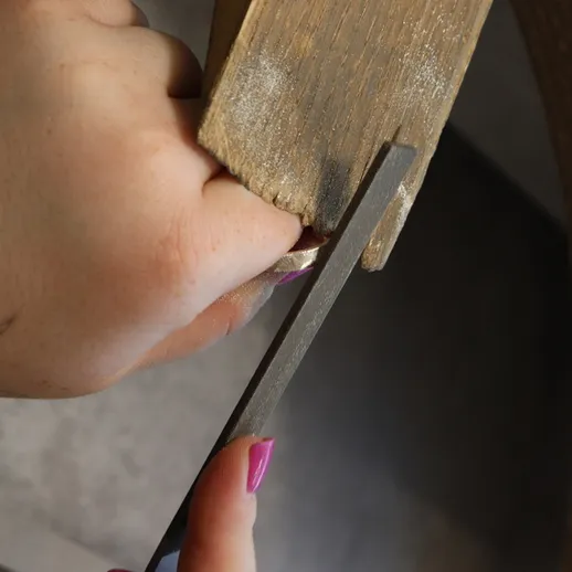 Работа с деревом: мастер использует напильник для обработки поверхности в мастерской