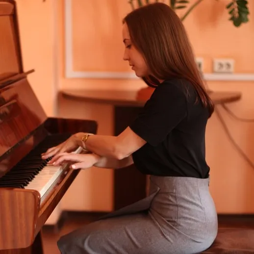 Женщина играет на пианино в уютной комнате с оранжевыми стенами в вечернее время