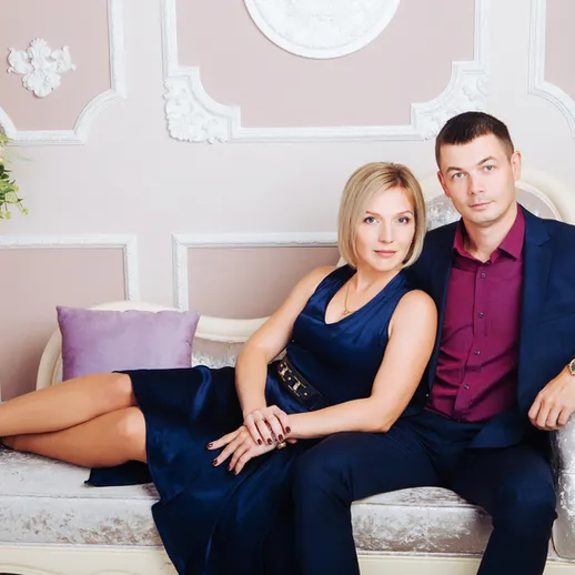 Пара позирует в элегантной одежде в интерьере с роскошным диваном и цветами