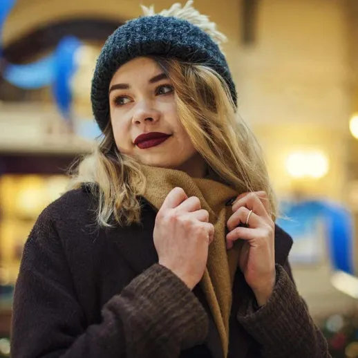 Простая прогулка девушки в зимней шапке и теплом шарфе в праздничной атмосфере магазина