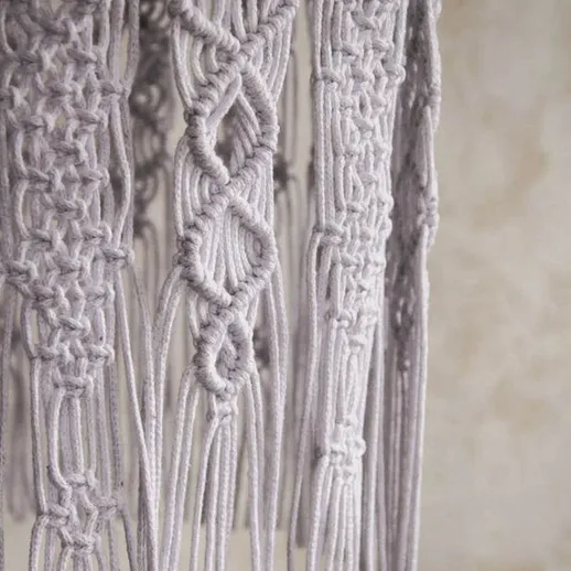 Макраме в интерьере: узорчатая подвеска из белого шнура на фоне светлой стены
