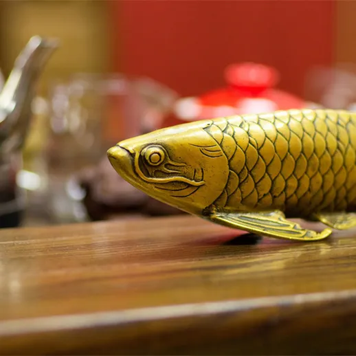 Золотая рыбка на деревянном столе в уютном кафе с яркими чашками и чайниками на заднем плане