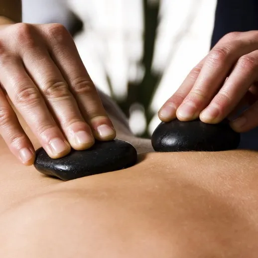 Массаж с горячими камнями в спа-салоне на фоне уютной обстановки во время релаксации