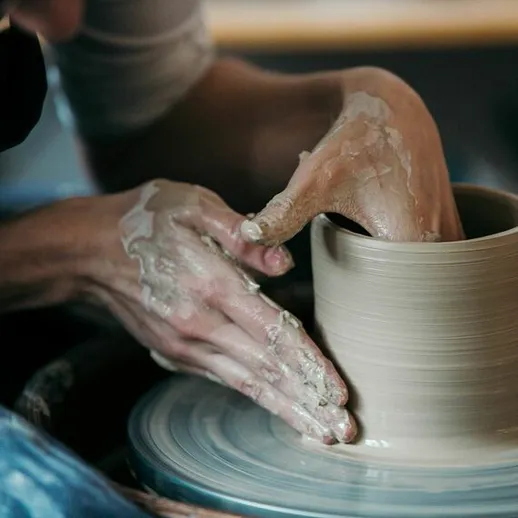 Изготовление глиняного изделия на гончарном круге в мастерской на свежем воздухе в солнечный день