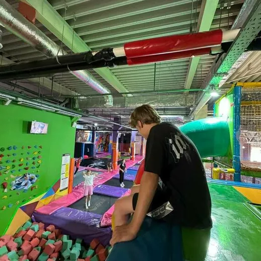 Подростки наслаждаются активными играми в парке отдыха с батуем и мягким приземлением