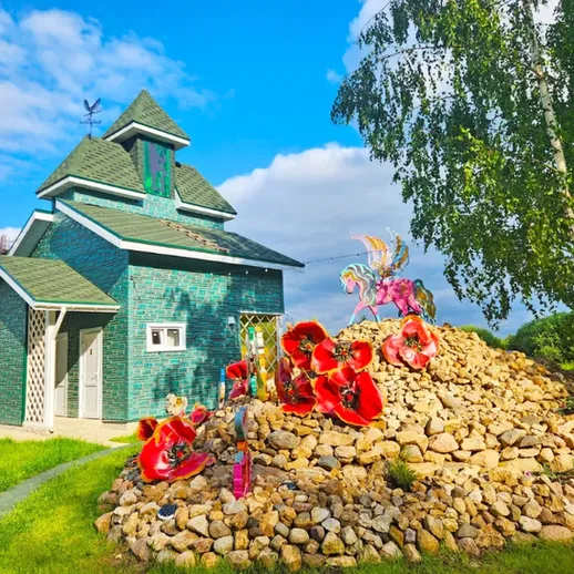 Очаровательный домик с зеленой крышей и яркими цветами на приусадебном участке в солнечный день