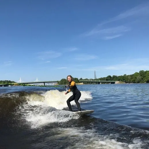 Серфингистка наслаждается катанием на волнах реки в ясный солнечный день под открытым небом