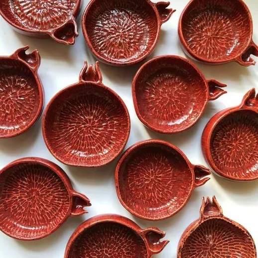 Керамические тарелки в виде граната, расположенные на белом фоне, создают эффект художественного оформления