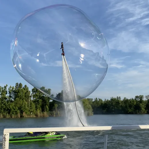Летящий человек на водном мотоцикле рядом с гигантским пузырем на реке в солнечный день