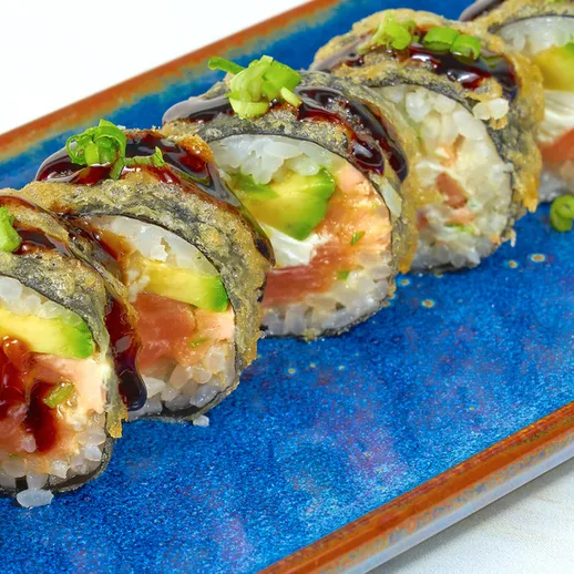 Справжній суші на синей тарелке подаются с авокадо и лососем на столе в ресторане японской кухни