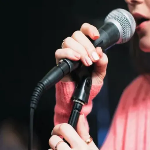 Исполнитель держит микрофон во время выступления на сцене в клубе вечером