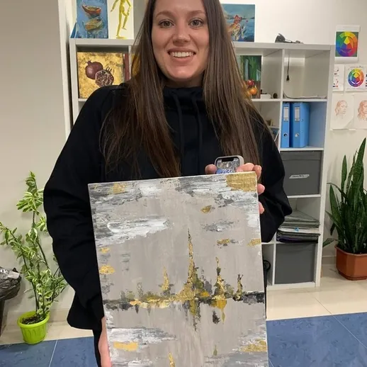 Молодая женщина с картиной в арт-студии, освещенной дневным светом, в уютной обстановке