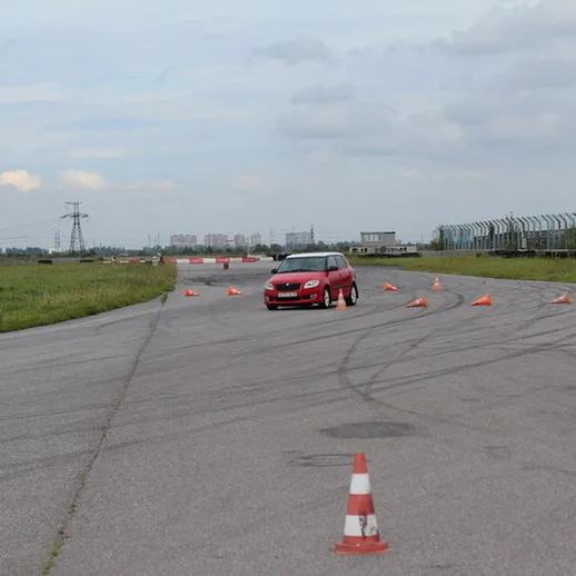 Красный автомобиль проходит маршрут на тренировочной площадке в светлое время суток в России
