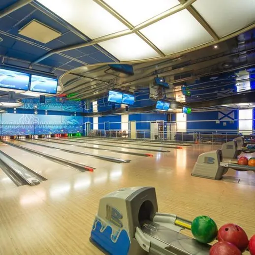 Современный боулинг с яркими шарами и экранами на стенах в развлекательном комплексе