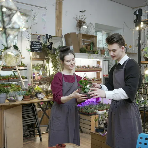 Молодые люди ухаживают за растениями в цветочном магазине во время рабочего дня