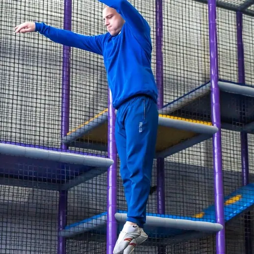 Мужчина в синем костюме прыгает с высоты в игровой комнате для детей в помещении