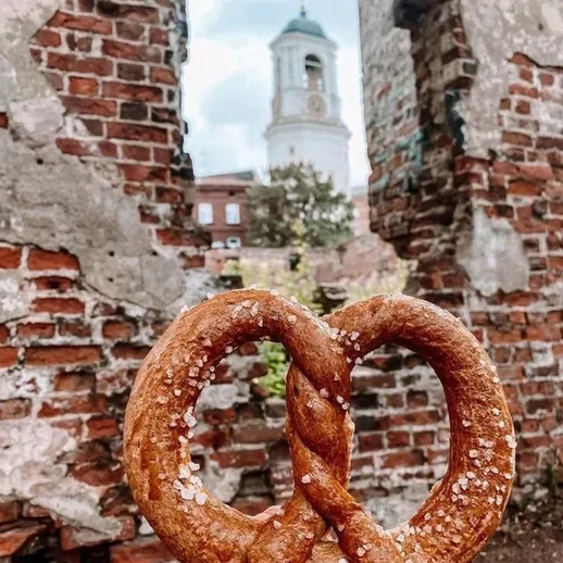 Крендель на фоне исторических развалин с башней колокольни в ясный день