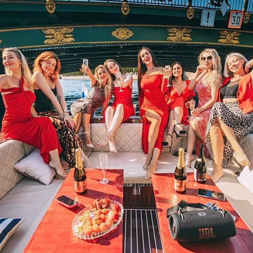 Групповая фотография девушек в красных платьях на лодке во время вечеринки на воде