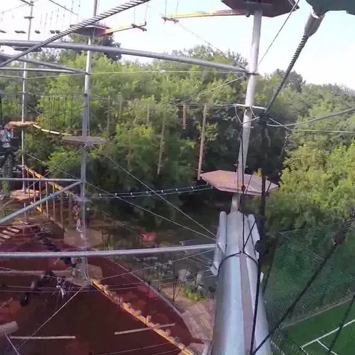 Соревнование на веревочном парке в пригороде под открытым небом с участниками, преодолевающими препятствия на высоте