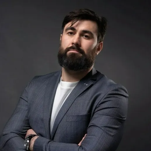 Уверенный мужчина с бородой в деловом костюме на нейтральном фоне