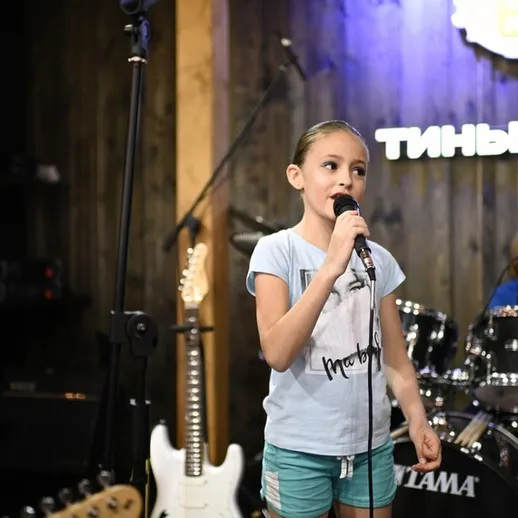 Девочка поет на сцене перед музыкантами в кофейне