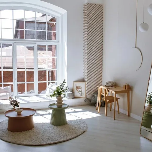 Современный интерьер светлой гостиной с большими окнами и зеркалом на стене