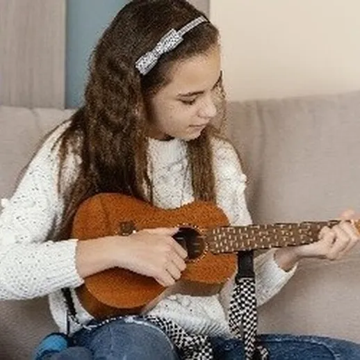 Девочка играет на укулеле в уютной гостиной