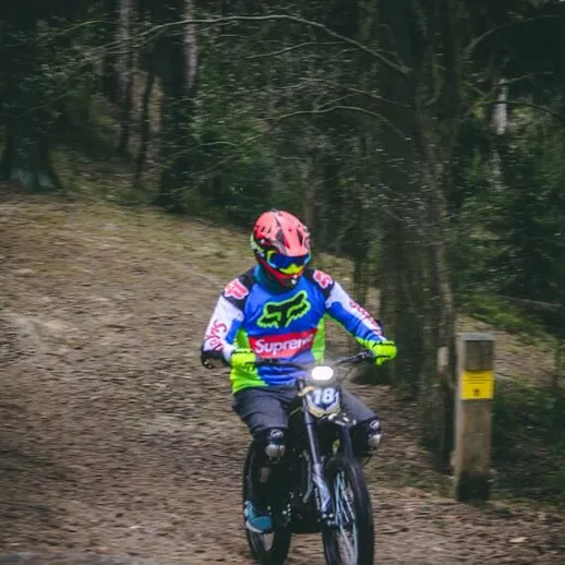 Мотоциклист на тропе в лесу, преодолевающий сложный участок во время соревнования в воскресный день