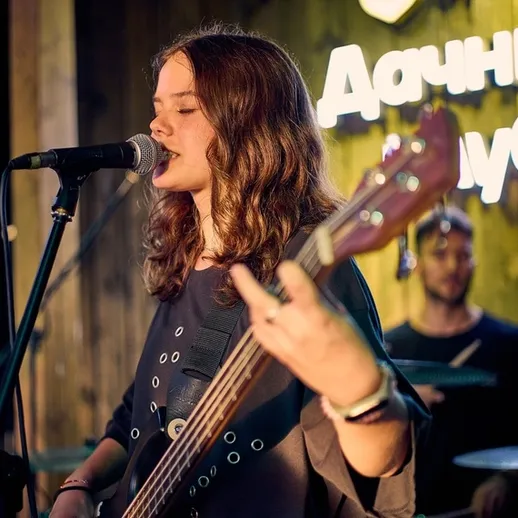 Молодая музыкантка исполняет живую музыку в клубе на берегу реки в вечернее время